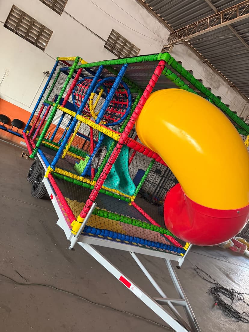 Kid Play Móvel com escorregador tubular vermelho e amarelo sobre carreta móvel